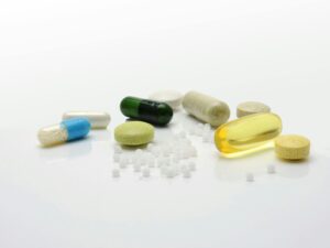 Close-up of various pills and capsules on a white surface, representing healthcare.